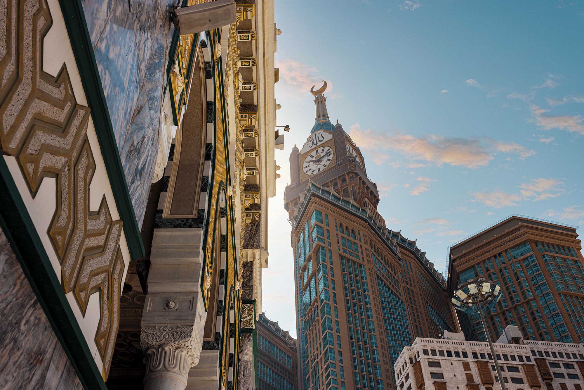 A low-angle view of the Abraj Al Bait clock tower and surrounding skyscrapers from the courtyard of Al-Masjid Al-Haram.