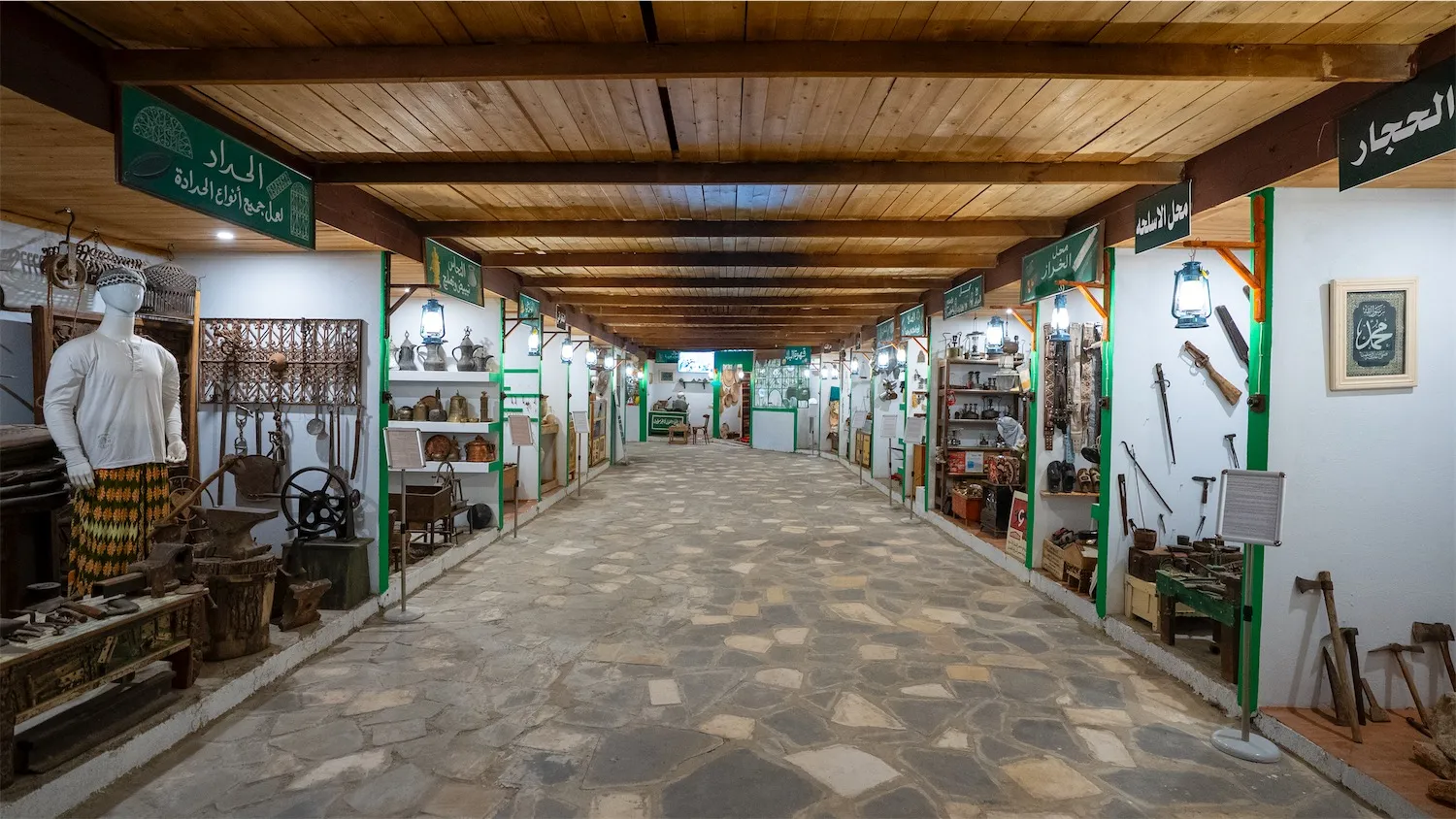 A wide view of the main corridor inside Heraf Alawalin Museum in Makkah, featuring various heritage stalls and traditional crafts.