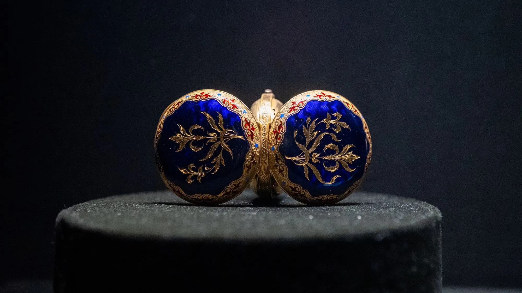 A beautifully decorated blue and gold antique pocket watch displayed as a historical artifact in the Clock Tower Museum in Makkah