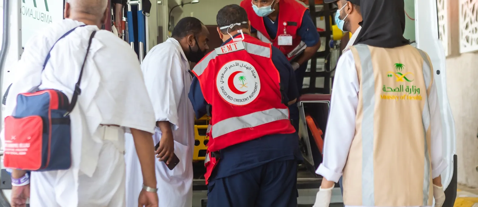 Medical personnel from the Saudi Red Crescent Authority and the Ministry of Health assisting a patient, representing healthcare services in Saudi Arabia.
