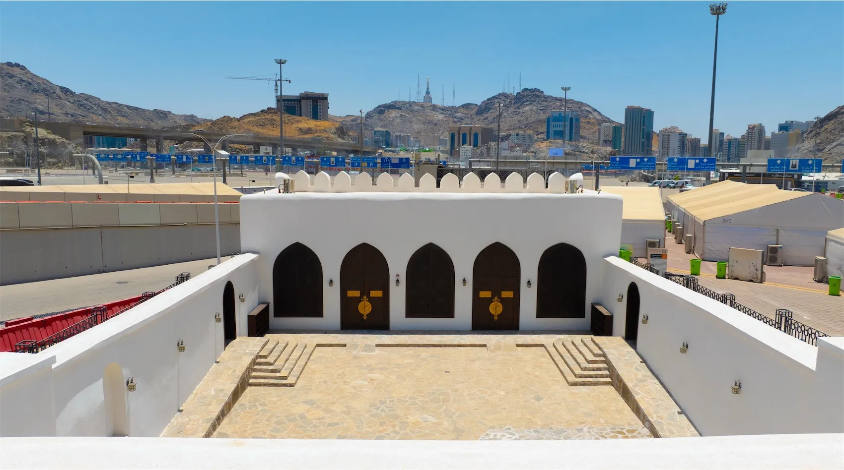 Wide view of Al-Bay'ah Mosque in Makkah with the city skyline and mountains in the background.